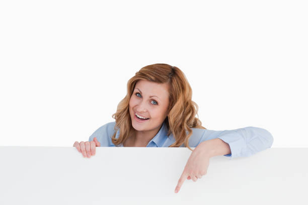 istock Happy blondhaired woman standing behind a white board 826520758