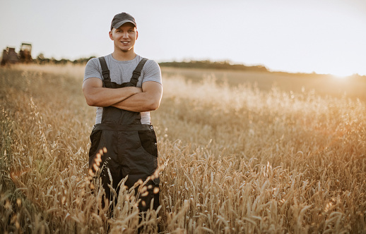 Front view of farmer standing in the middle of field, crossarm