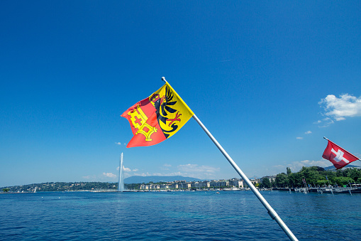 Flag of the Geneva Canton in the city center of Geneva, on the Leman lake. The iconic Jet d'Eau (Water Jet) can be seen in the background