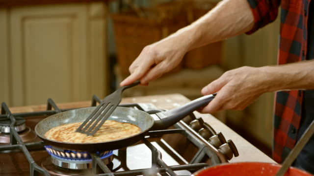 LD male chef making crepes in a cooking show and flips them into the air