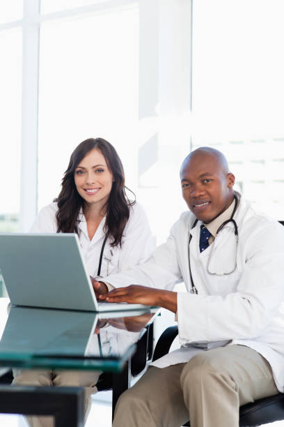 istock Smiling doctor working on a laptop while accompanied by his colleague 826561096
