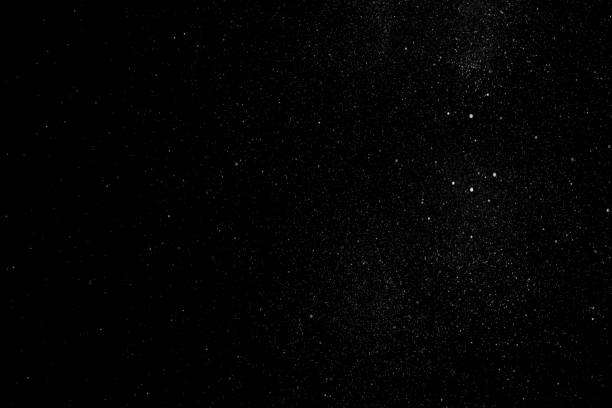 White particles and ink slowly moving in water on black background