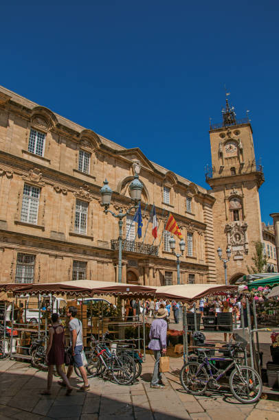 plaza con tienda, gente y torre del reloj en aix-en-provence. - market square clock tower bicycle flag fotografías e imágenes de stock