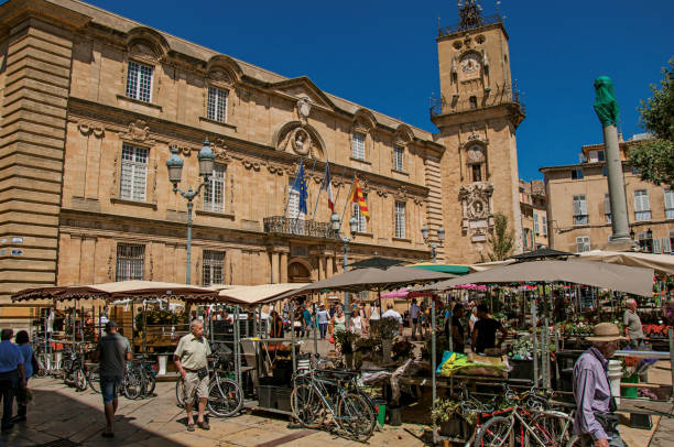 plaza con tienda, gente y torre del reloj en aix-en-provence. - market square clock tower bicycle flag fotografías e imágenes de stock