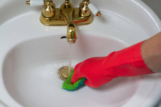 istock Man Cleaning Bathroom Sink with Red Rubber Glove 826574824