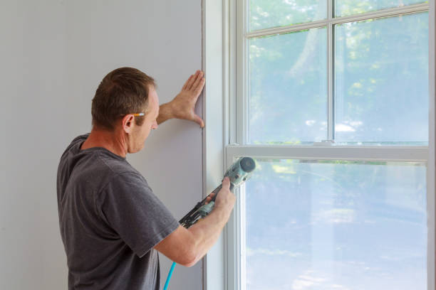 istock Carpenter using nail gun to moldings on windows, framing trim, 826581922
