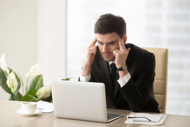 istock Frustrated businessman suffering from headache migraine at workplace, massaging temples 826582474