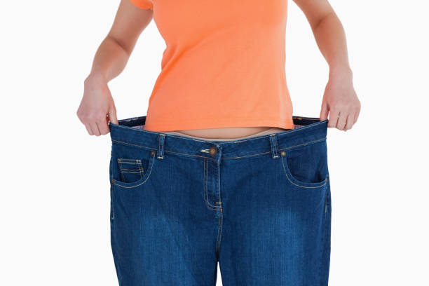 тонкий женщина показывает, сколько веса она потеряла - adult abdomen blue the human body стоковые фото и изображения
