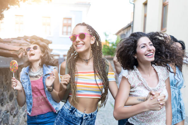 Group of cheerful friends having fun on streets in old town, holding hands and dancing.