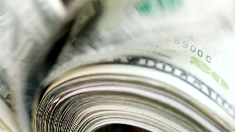 Woman fanning through large stack of USA currency.