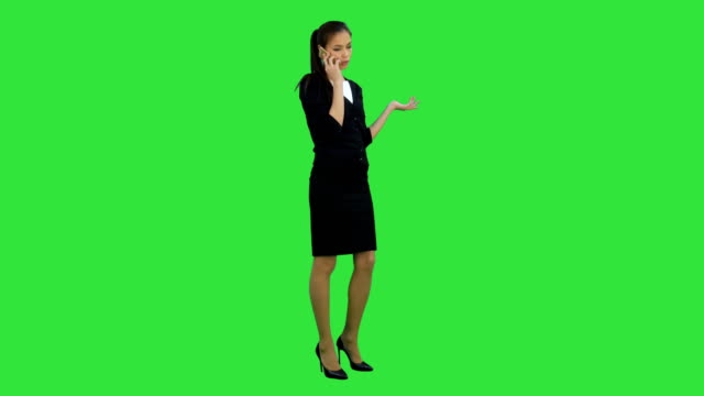 Skeptical and unhappy young woman talking on mobile phone on a Green Screen, Chroma Key