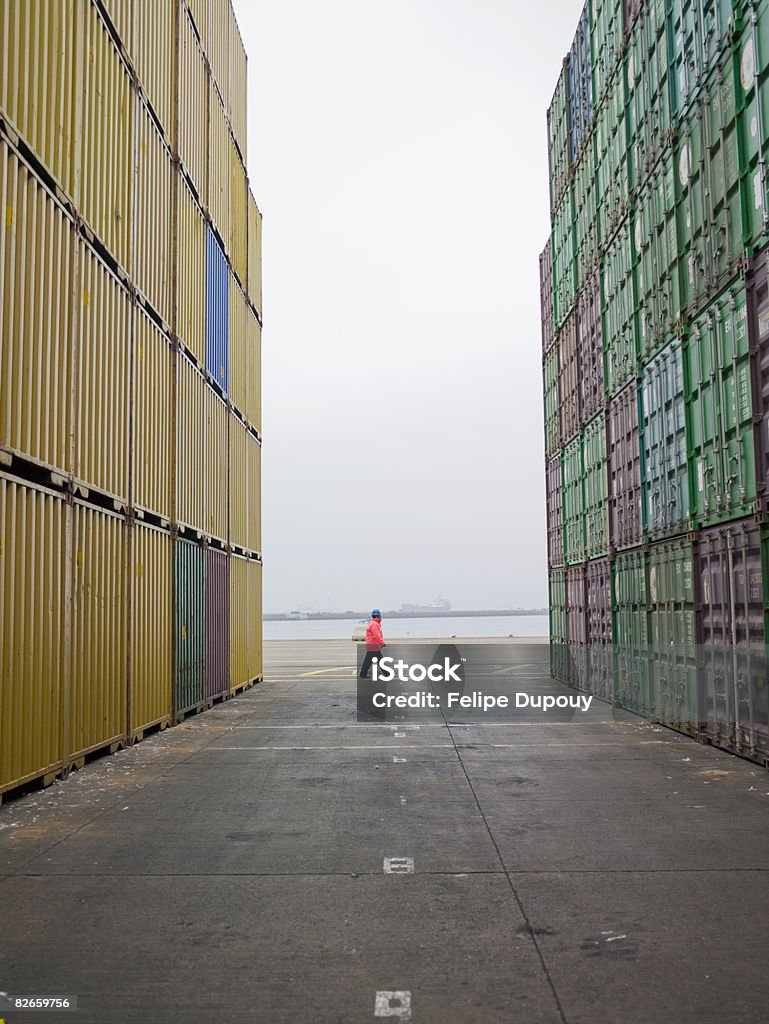 Man standing between containers in a shipping yard  Cargo Container Stock Photo
