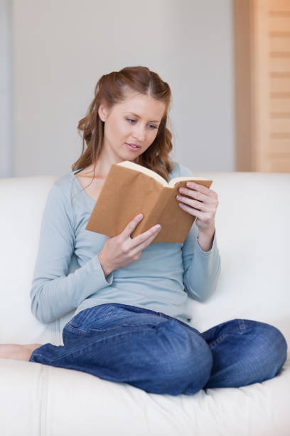istock Woman on the sofa focused on her book 826597854