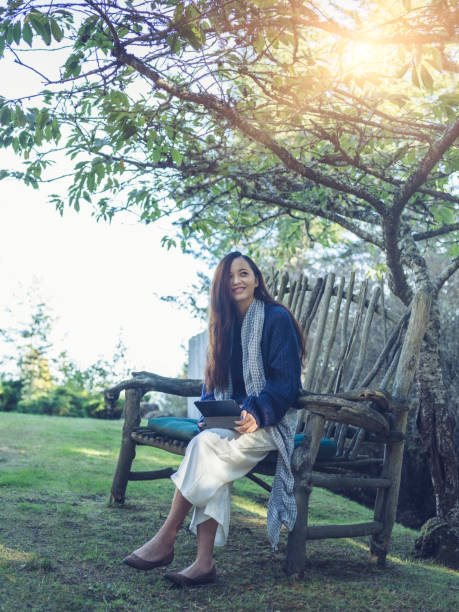 istock young asian woman using tablet,sitting on the garden bench at backyard 826598160