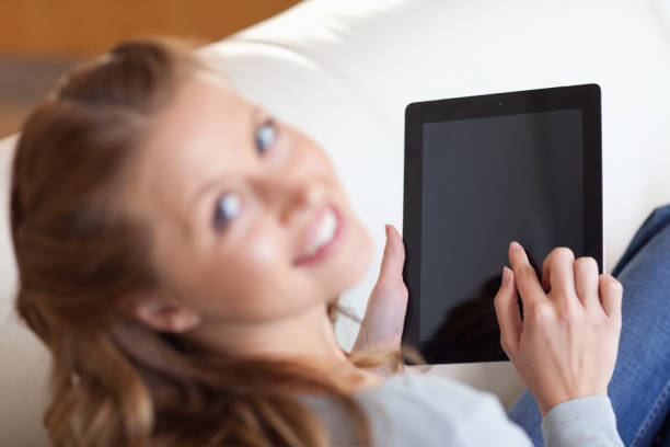 istock Above view of smiling woman using tablet on the sofa 826598322