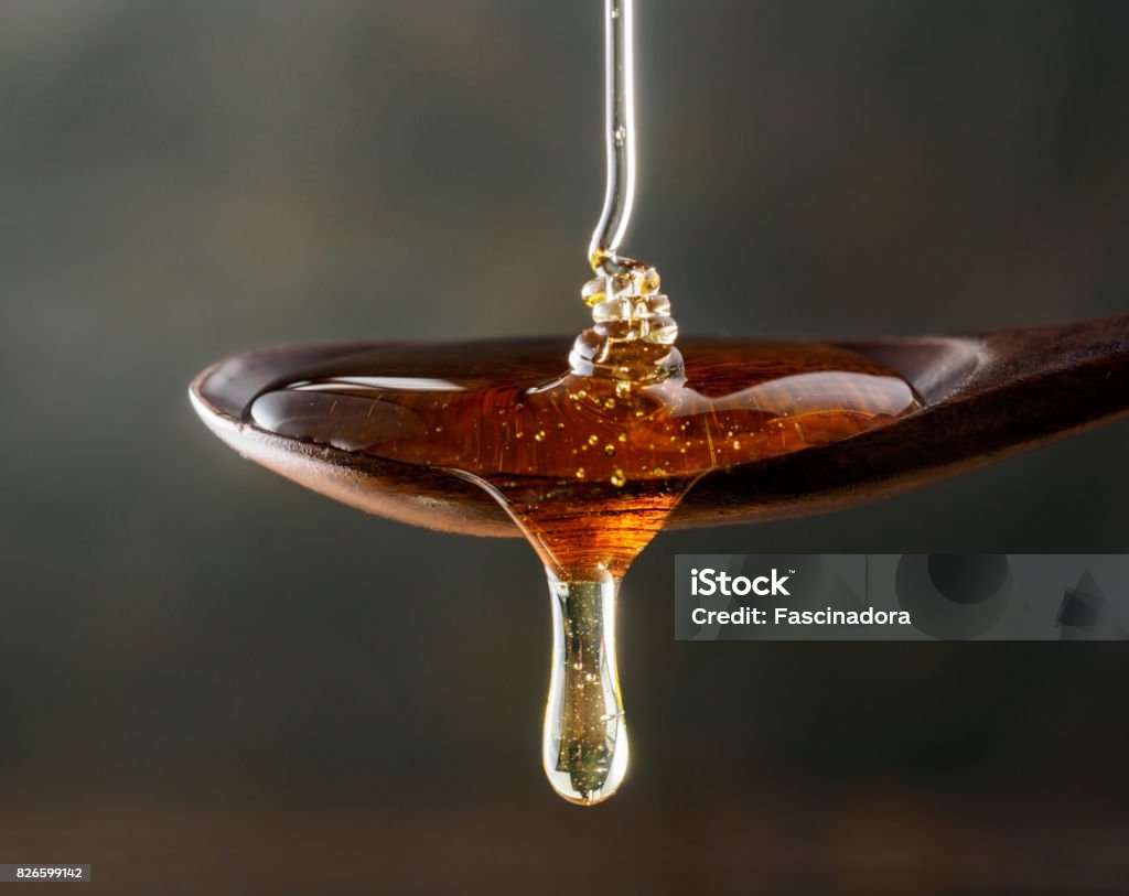 Verser sur la cuillère en bois et dégoulinant de cuillère au miel - Photo de Miel libre de droits