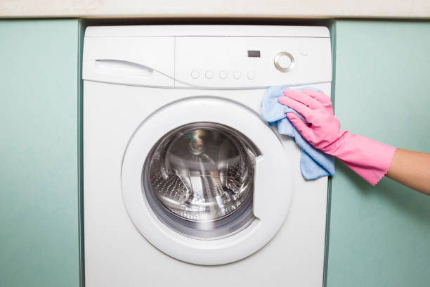 istock Hand in rubber protective glove with dry microfiber cloth carefully cleaning a washing machine in the bathroom. Early spring cleaning or regular clean up. Maid cleans house. 826638026