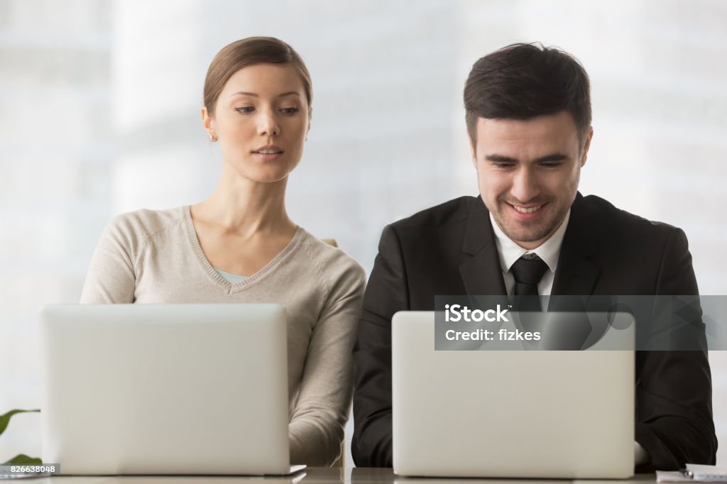 Interesados curiosa empresaria mirando la pantalla del ordenador portátil de empresario, espionaje corporativo - Foto de stock de Curiosidad libre de derechos