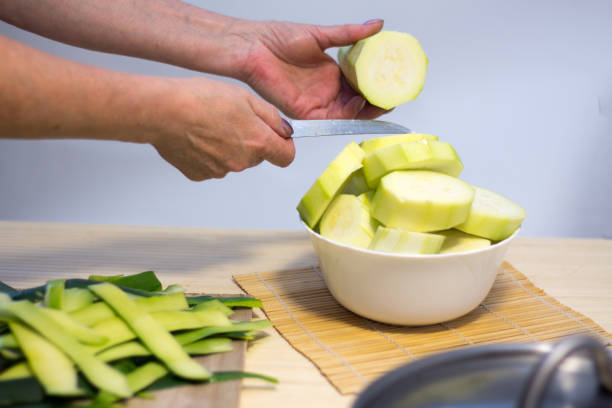 istock Woman cooking and slicing fresh vegetables on a rustic kitchen worktop, healthy eating concept, flat lay 826645738
