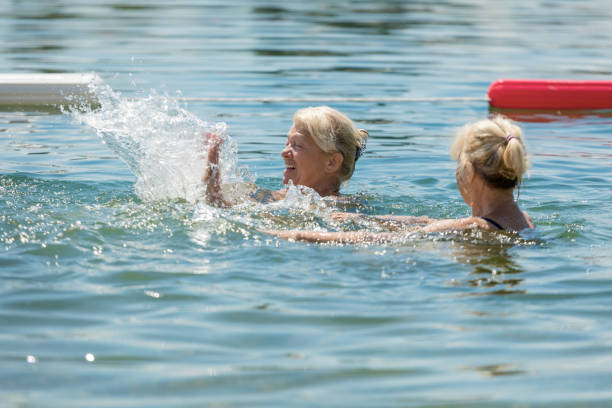 Senior women splashing each other while swimming