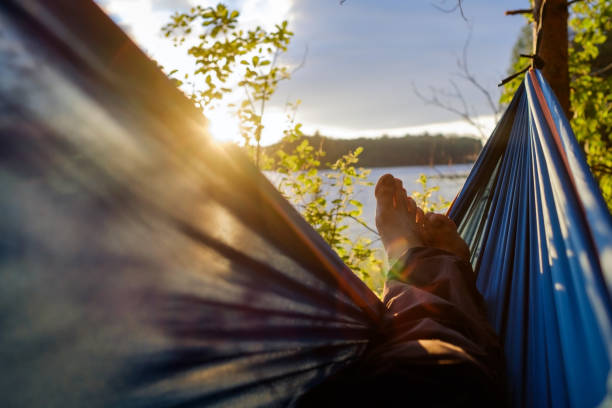 Man relaxing in the hammock. View on lake and sunrise