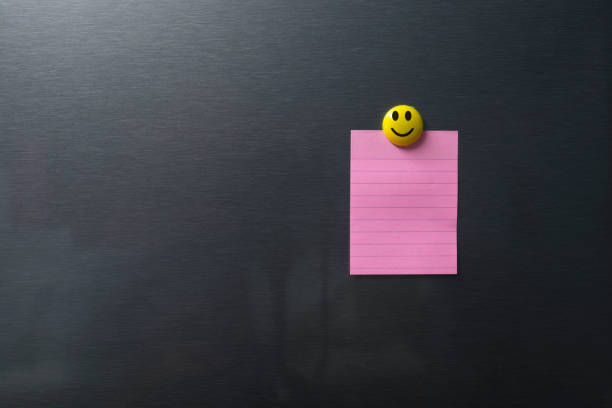 Empty pink paper on refrigerator door with smilling face on magnet.