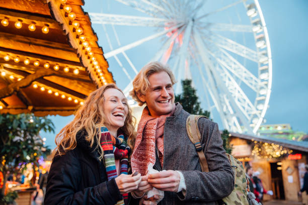 Couple Enjoying Christmas Fair Happy couple are eating sweets and watching entertainment at the christmas fair and market. hyde park london photos stock pictures, royalty-free photos & images