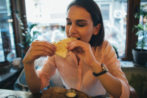 Woman eating a tortilla sandwich at a restaurant.