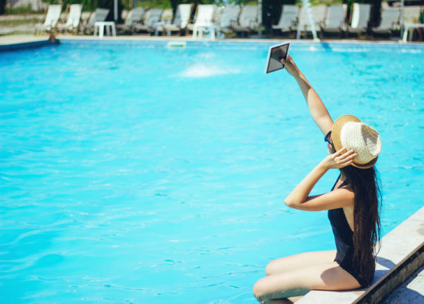 istock woman taking a selfie with tablet by the pool 826674362
