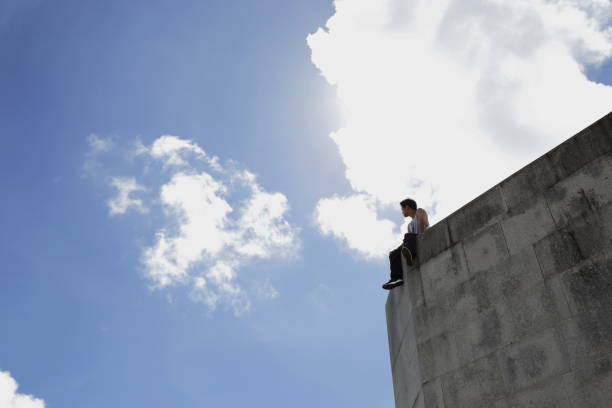 istock Young man sitting on big concrete wall 826677294