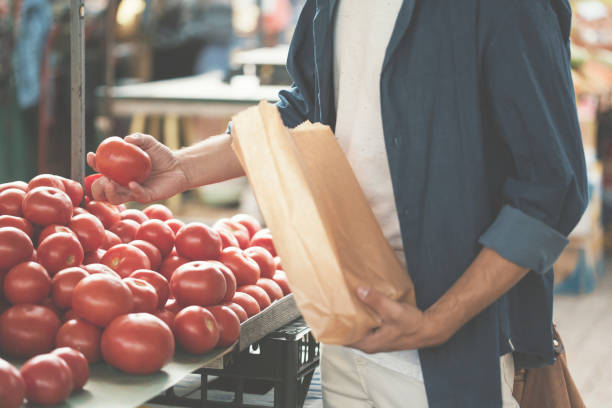 istock Young man picking up tomatoes on market 826686016