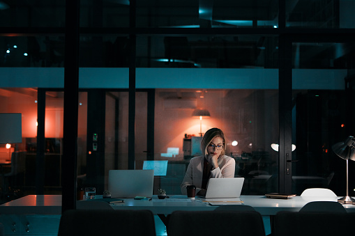 Shot of a businesswoman using a laptop at her desk during a late night at work