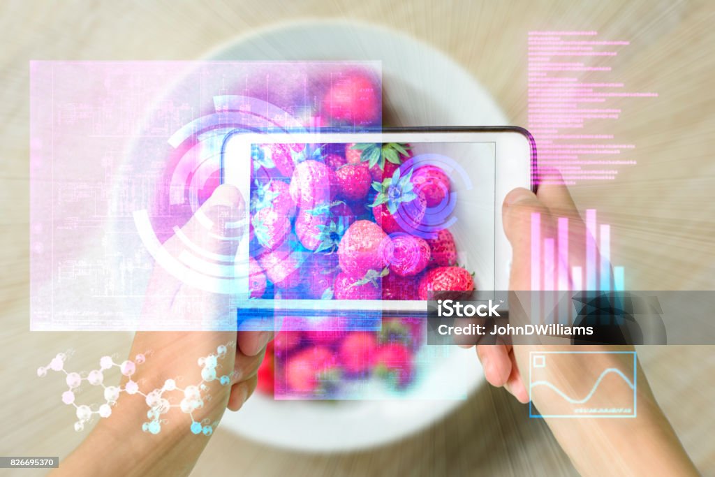 Smart Device Augmented Reality Food Checker Woman holding a smart device uses reality augmentation to examine a pile of strawberries Food Stock Photo