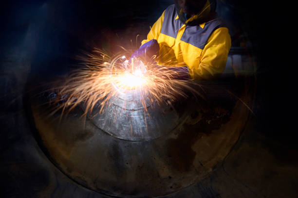 istock Industrial worker welding metal and many sharp sparks inside piping construction with confined space . 826695556