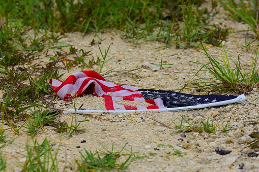 Discarded American flag partly covered in dirt. Photo taken in Nassau county, Florida