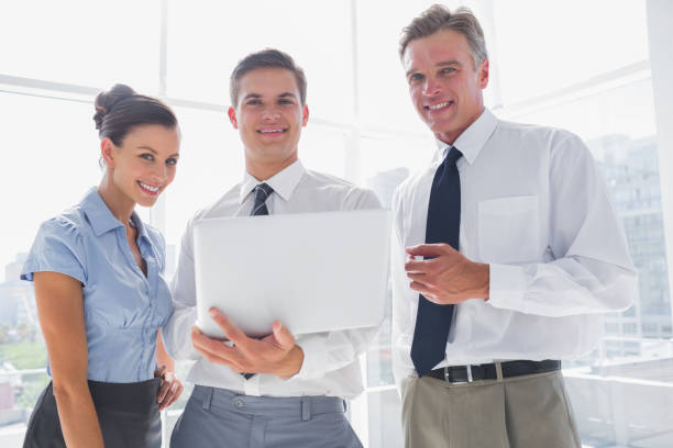 istock Three smiling business people holding a laptop 826704246