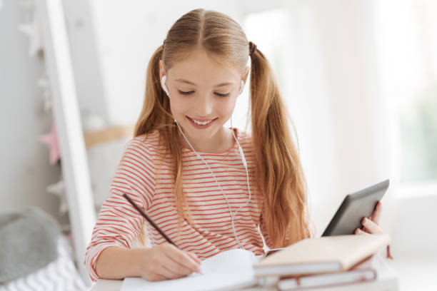 istock Diligent female pupil doing homework and listening music 826712216
