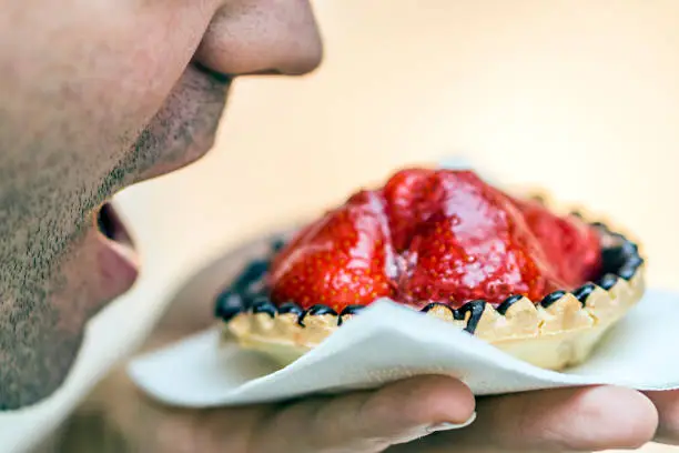 A man is eating a strawberry tart