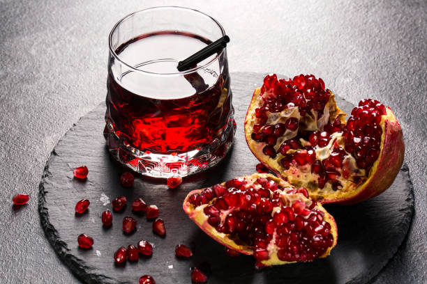 istock Bright garnet drink and a red pomegranate on a light gray background. Exotic ingredients for summer cocktails. Healthy delicacy. 826717086