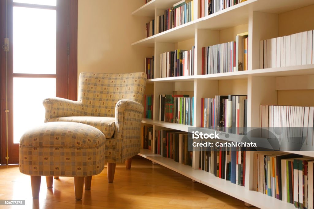 Home library Home library with arm chair. Clean and modern decoration. Natural light coming from window. Residential Building Stock Photo