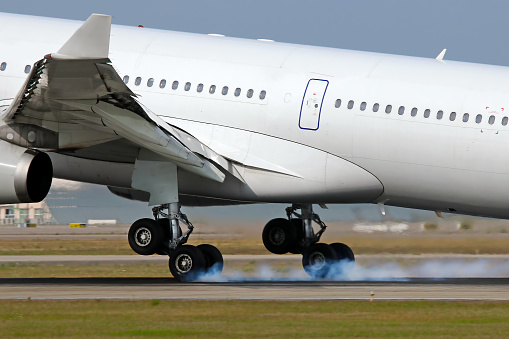 Photo of aircraft landing gear wheels emitting smoke while touchdown on landing