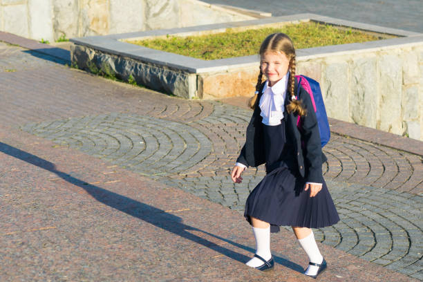 istock Girl in school uniform with a backpack rises a ladder 826720218