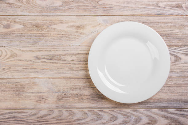 istock Empty white plate on wooden table. Template for your design. 826723156