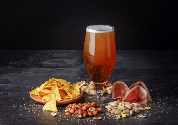 istock Beer and salty snacks on a black table. Alcoholic drink with nuts and chips. Celebration concept. Traditional snacks. Copy space. 826724426