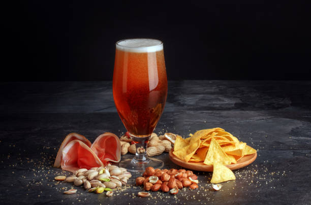 istock Beer and salty snacks on a black table. Alcoholic drink with nuts and chips. Celebration concept. Traditional snacks. Copy space. 826724472