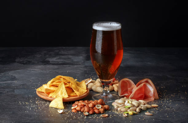 istock Beer and salty snacks on a black table. Alcoholic drink with nuts and chips. Celebration concept. Traditional snacks. Copy space. 826724520