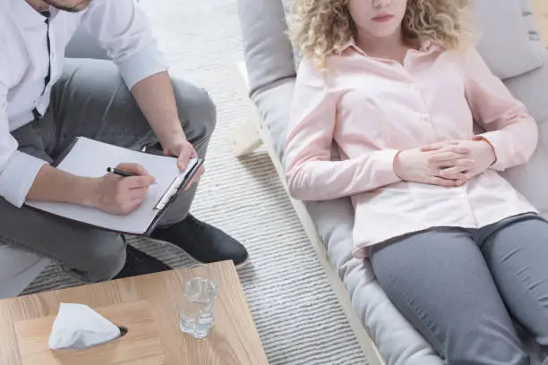 Woman in hypnosis lying on psychotherapist sofa