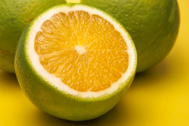 istock Green Tangerine Orange Slice on Yellow Background 826728228