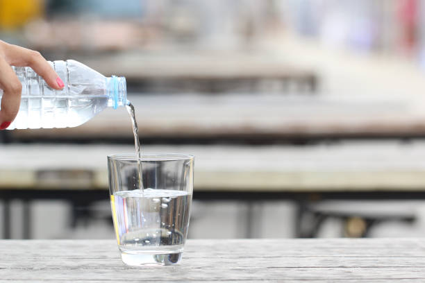 istock Pouring pure water from bottle on table 826728624