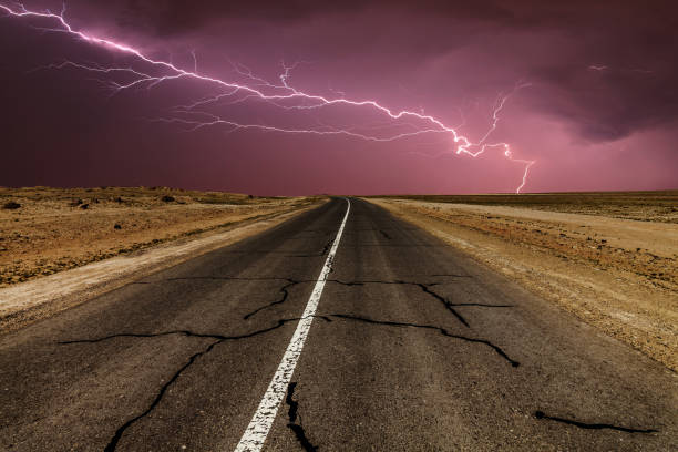 istock Stormy country road at night, with intense lightning strikes. 826753318